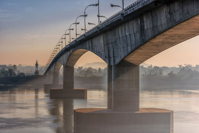 Arch bridge over river against sky during sunset