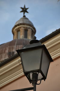 Low angle view of street light by building against sky