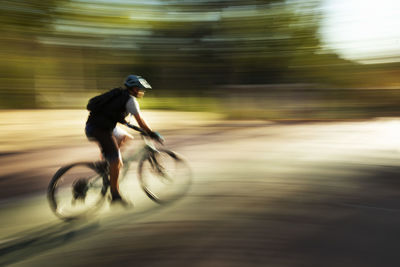 Blurred motion of man riding bicycle on road