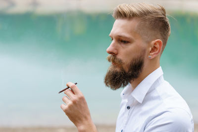 Handsome serious guy, young thoughtful man smokes, heating tobacco products