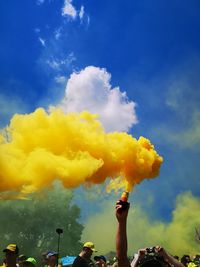 Low angle view of hand against yellow sky