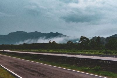 Road amidst field against sky