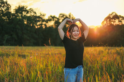 Portrait of woman with arms raised standing on land