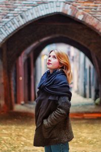 Young woman looking up while standing at archway