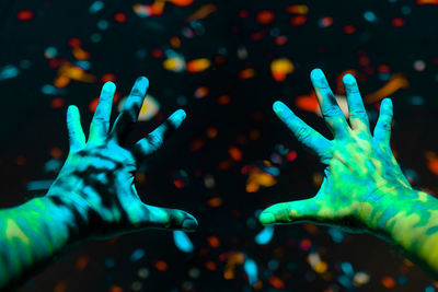 Close-up of hands against illuminated lights