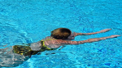 High angle view of woman swimming in pool on sunny day