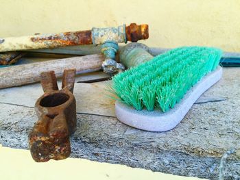 Close-up of brush by rusty metallic equipment on weathered plank