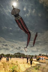 People enjoying on field against cloudy sky