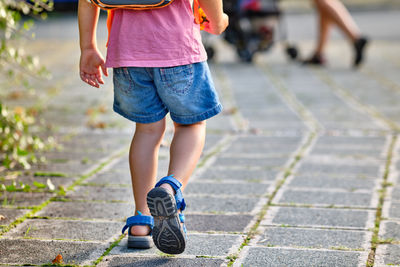 Low section of girl walking on footpath