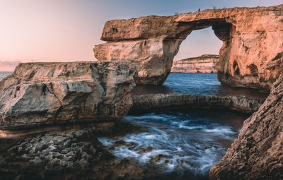 Rock formations by sea against sky