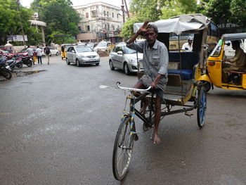 Man riding bicycle on road in rain