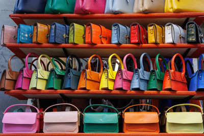 Small women's colorful handbags of various kinds hanging on a display stand.