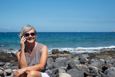 Smiling senior woman sitting at beach