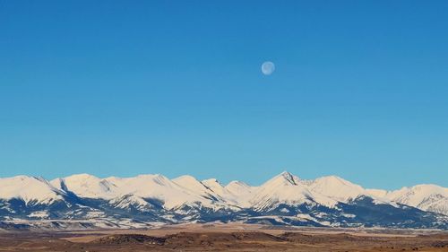 Scenic view of snowcapped mountains against clear blue sky