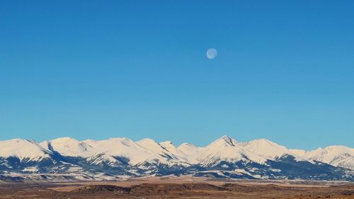 Scenic view of snowcapped mountains against clear blue sky