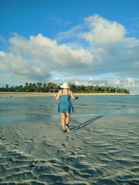 Rear view of man on beach against sky