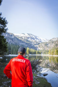 Rear view of man looking at waterfall against sky