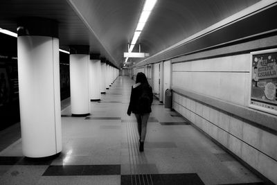 Rear view of woman standing on illuminated corridor