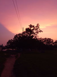 Silhouette trees on landscape against romantic sky at sunset