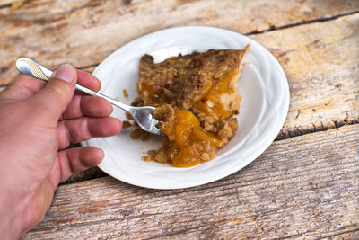 Hand using a spoon to eat apricot pie
