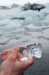 Hand of person holding ice above water