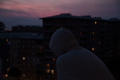 Rear view of man with umbrella against sky at night