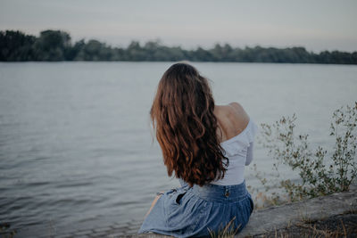 Rear view of woman looking at lake against sky