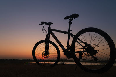 Silhouette bicycle against clear sky during sunset