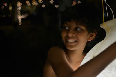 Smiling boy holding lighting equipment while standing outdoors at night