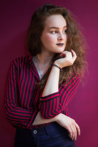 Beautiful woman looking away against red wall