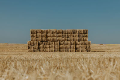 Hay bales on field against clear sky