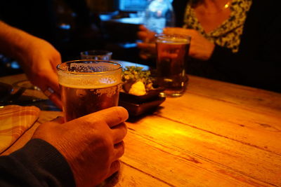 Cropped hand of person holding drinking glass on table