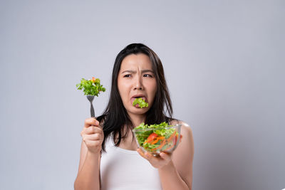 Portrait of woman holding ice cream against white background