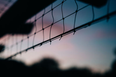 Close-up of silhouette net against sky at sunset