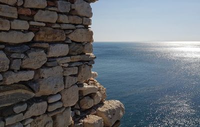 Stone wall by sea against sky