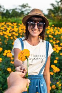 Cropped hand of friend giving flower to woman