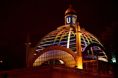 Low angle view of illuminated built structure against clear sky at night