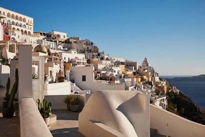 Buildings by sea against clear blue sky