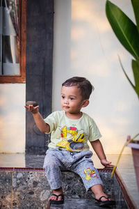 Cute boy looking away while sitting outdoors