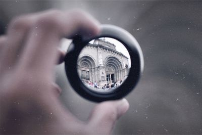 Historic building seen through lens held by hand