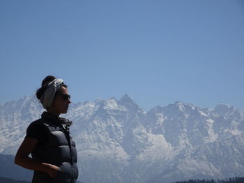 Man standing on snowcapped mountain against clear sky
