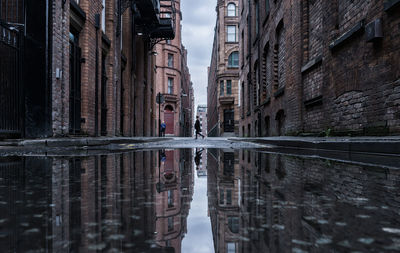 Reflections of buildings in puddle at street