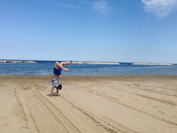 Rear view of man standing on beach against clear sky