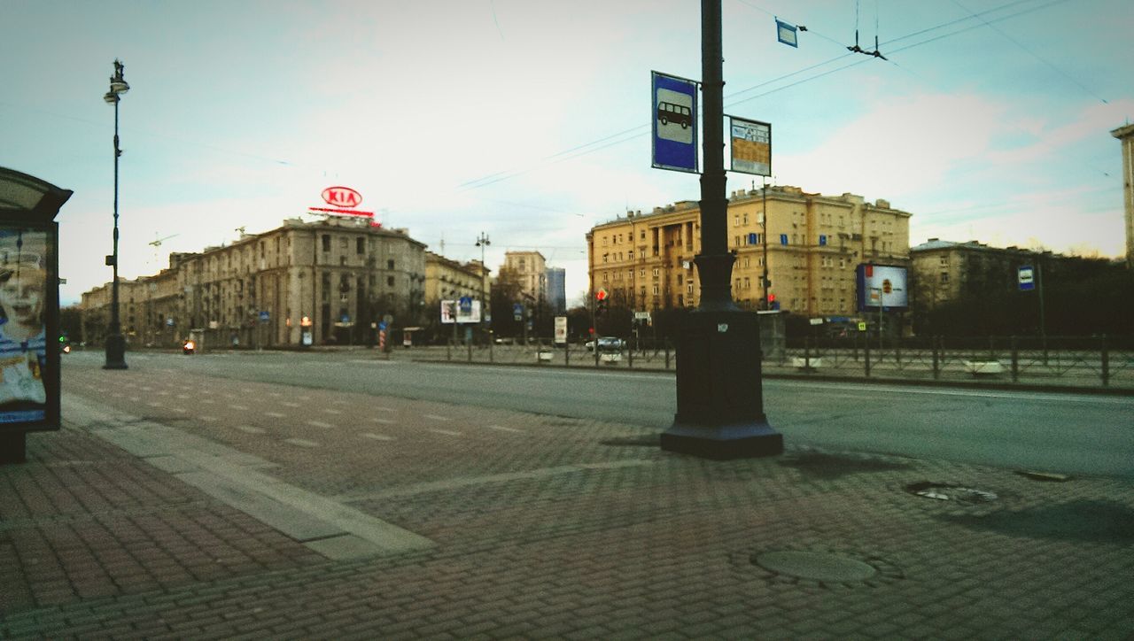 architecture, building exterior, built structure, street, city, sky, road, street light, transportation, road marking, sidewalk, incidental people, city life, road sign, city street, guidance, the way forward, outdoors, sunlight, cobblestone