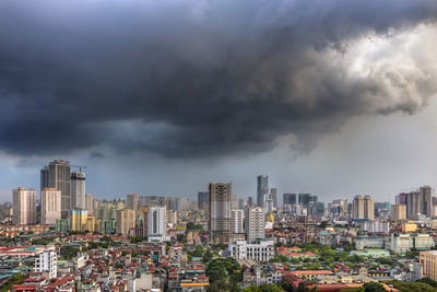 Aerial view of buildings in city against storm clouds