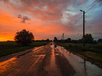 Road amidst trees against sky during sunset