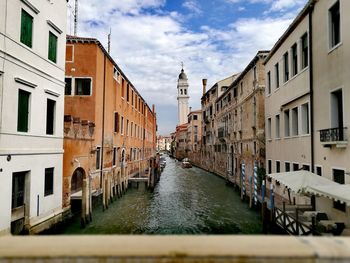 Canal amidst city against sky