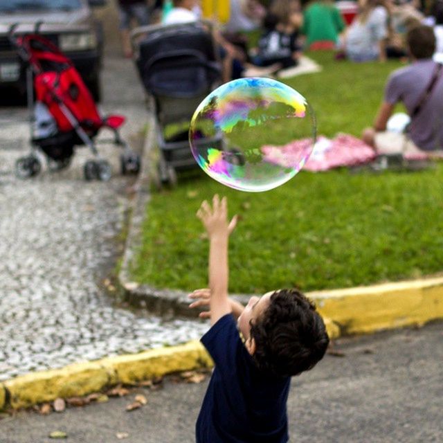 lifestyles, leisure activity, focus on foreground, street, holding, bubble, person, childhood, multi colored, incidental people, standing, playing, girls, balloon, rear view, close-up, sphere, celebration