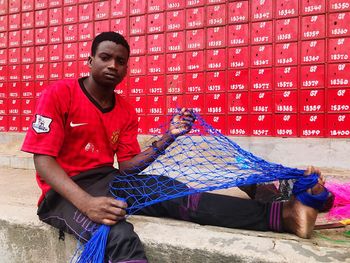 Portrait of young man standing against red wall