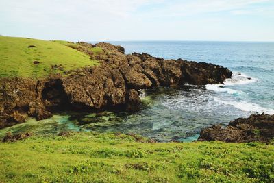 Scenic view of cliff by sea against sky